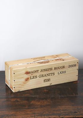 une caisse en bois sur laquelle est collée une étiquette de vin, posée sur une table