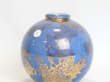 a blue vase with gold designs on it on a white surface