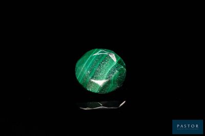 a close up of a green stone on a black surface
