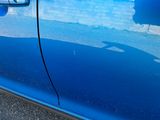 a close up of a blue car with a reflection on the side of it