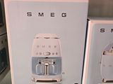 deux cartons contenant des machines à café Smeg sur une étagère dans un magasin