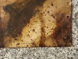 rusted piece of metal on the ground with a picture of a man on a horse