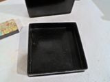 une petite boîte noire posée sur une table, à côté d'une autre petite boîte noire