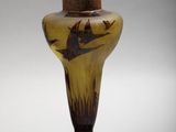 a brown vase with a bird on it on a white surface