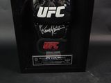 a signed ufc glove is displayed in a black frame
