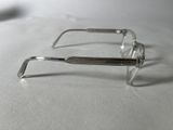 pair of clear glasses on a white surface with a black object in the background