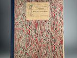 un vieux livre à la couverture rouge et bleue posé sur une table