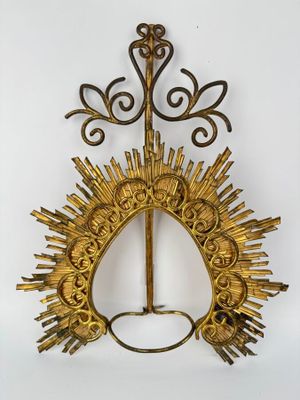 a gold sunburst hanging on a wall next to a white wall
