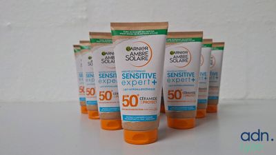 quatre tubes de crème solaire posés sur une surface blanche