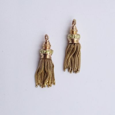 une paire de boucles d'oreilles à pompons dorés sur fond blanc
