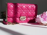 a pink purse sitting on a white table next to a pink flower