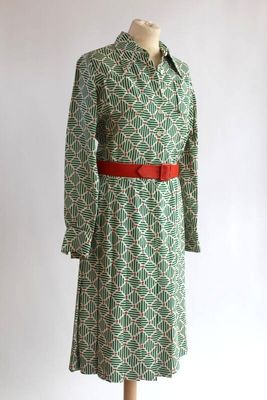 une robe verte et blanche avec une ceinture rouge sur un mannequin