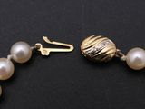 an image of a pearl bracelet with a gold clasp on a black surface