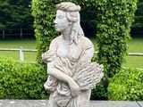 a statue of a woman holding a fan in a garden