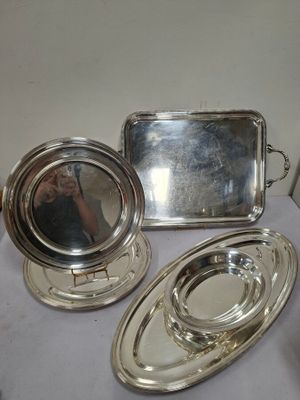 trois plateaux en argent et un miroir posés sur une table