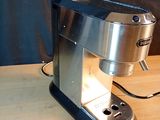 a silver coffee maker on a wooden table with a black background