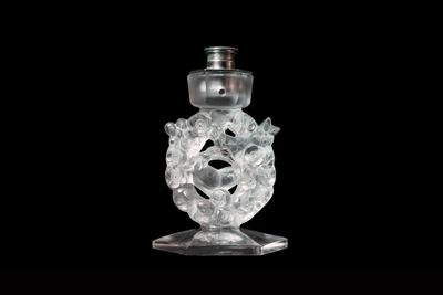 a clear glass bottle with a silver top on a black background