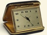 a small clock sitting in a case on a white surface