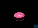 une photo d'une pierre rose posée sur une surface noire