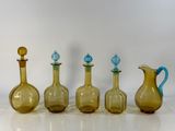 four different colored glass vases are lined up on a white surface