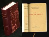 un vieux livre posé sur une table noire, à côté d'un livre rouge