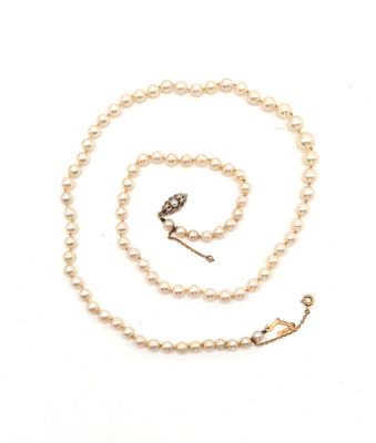 une photo d'un collier de perles blanches muni d'un fermoir en or