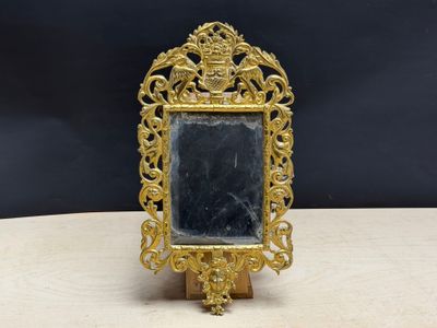 un cadre doré richement décoré, surmonté d'un miroir, posé sur une table