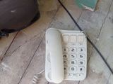 a white telephone sitting on the floor next to a speaker