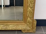 a large gold mirror sitting on the floor in front of a wall