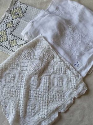 trois nappes blanches au crochet posées côte à côte sur un lit
