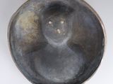 a metal bowl with a face on it on a white surface