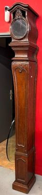 a tall wooden grandfather clock in front of a red wall