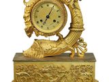 a gold clock that is sitting on a stand