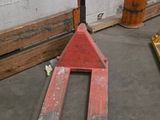 a fork lifter sitting in a warehouse with pallets in the background