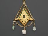 un gros plan sur un pendentif en or orné de perles vertes et blanches