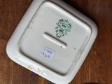 a white plate with a green design on it on a wooden table