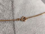 a close up of a gold chain bracelet on a pillow