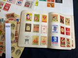 a book with stamps on it sitting on a table next to a pile of stamps