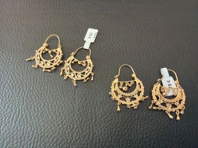 trois paires de boucles d'oreilles en or posées sur un fond en cuir noir