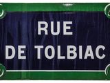 blue and green sign with white writing on it saying rue de tolbiac