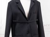 black coat on a mannequin dummy in front of a white wall