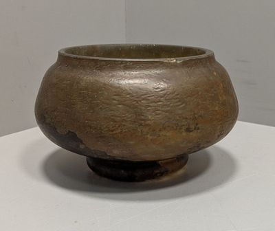 un petit bol marron posé sur une table blanche