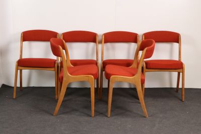 quatre chaises rouges sont alignées contre un mur blanc