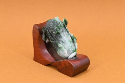 une figurine représentant une grenouille posée sur un socle en bois