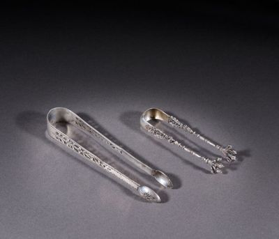 two silver spoons sitting on top of a table next to each other