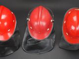 three red hard hats sitting on top of each other on a black surface