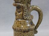 a small ceramic pitcher with a face on it