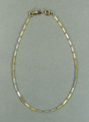 un gros plan d'un collier en or et en argent posé sur une surface grise
