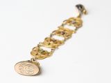 a close up of a gold bracelet with a coin on it
