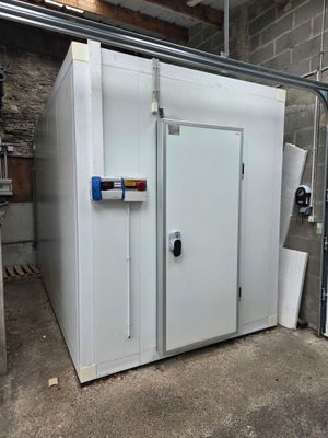 a large white freezer in a garage next to a wall
